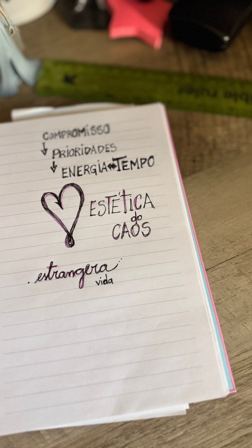 Visual: na página de um caderno, em caligrafia e letras de forma lê-se: compromisso, prioridades, energia=tempo. Um coração desenhado. Estética do Caos. estrangera vida. 